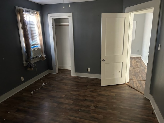 unfurnished bedroom featuring dark wood-type flooring, cooling unit, and a closet