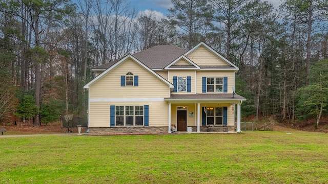 craftsman-style home with covered porch, roof with shingles, stone siding, and a front yard