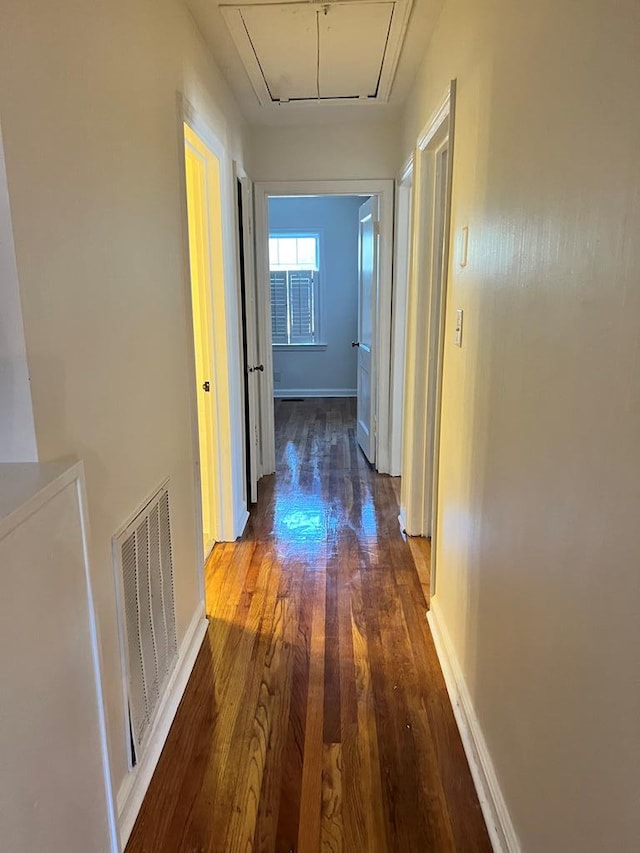 hall with baseboards, dark wood-style flooring, visible vents, and attic access