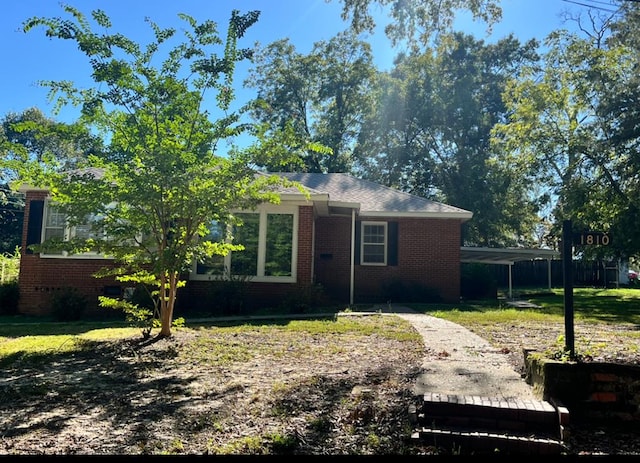 view of front facade featuring a carport, brick siding, and a front lawn