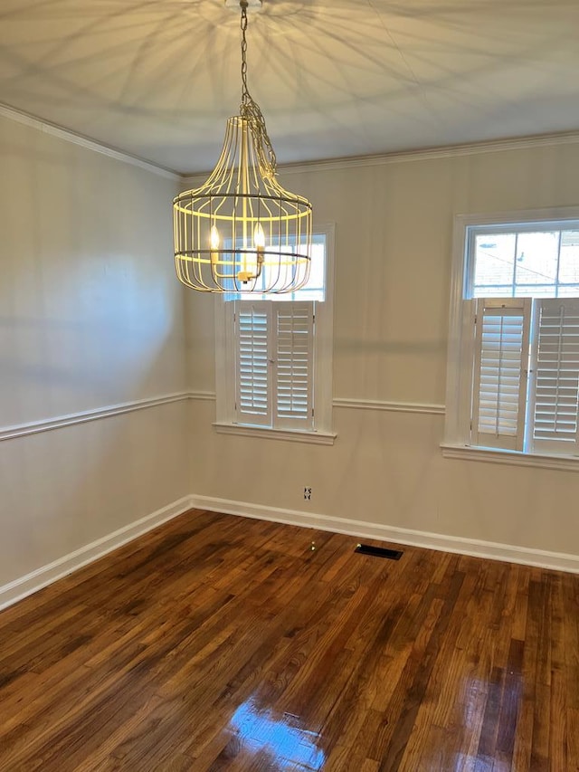 empty room featuring baseboards, an inviting chandelier, wood finished floors, and crown molding