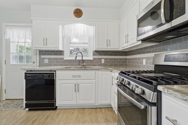 2608 5th Ave, Phenix City, AL 36867 - kitchen featuring appliances with stainless steel finishes, a sink, light wood-style flooring, and white cabinetry