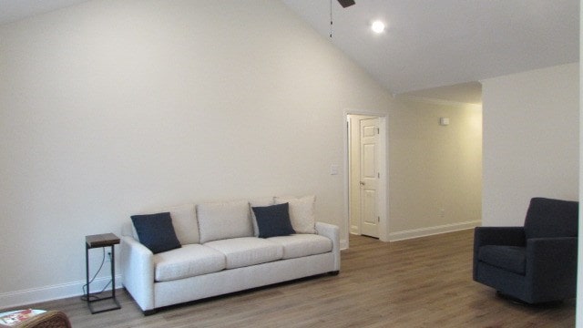 living room with hardwood / wood-style flooring, ceiling fan, and high vaulted ceiling