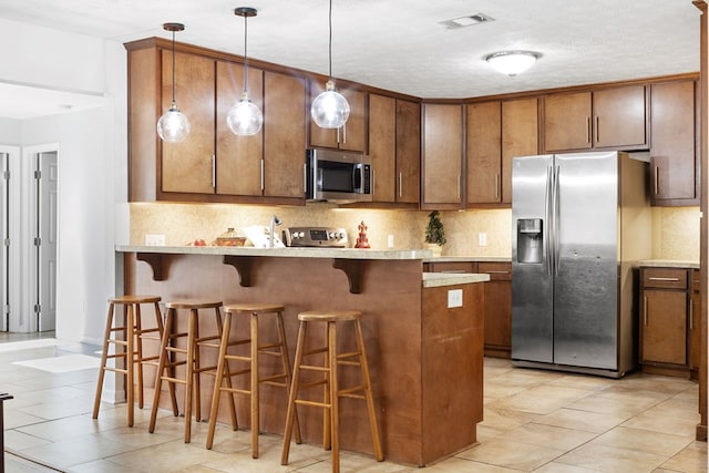 3796 Auburn Rd, Phenix City, AL 36870 - kitchen with appliances with stainless steel finishes, tasteful backsplash, a peninsula, light countertops, and a textured ceiling