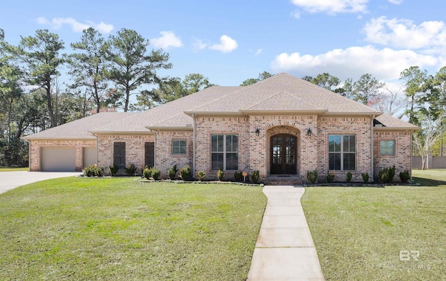 french provincial home featuring brick siding, roof with shingles, concrete driveway, an attached garage, and a front yard