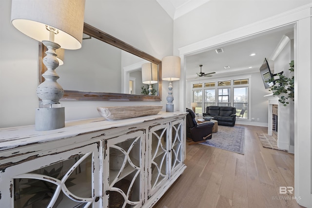 kitchen featuring crown molding, visible vents, a fireplace, and hardwood / wood-style floors