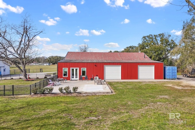 rear view of property featuring a garage, french doors, a patio, fence, and a yard