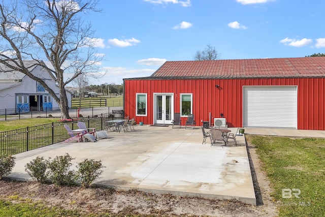 view of patio / terrace featuring a detached garage, fence, and french doors