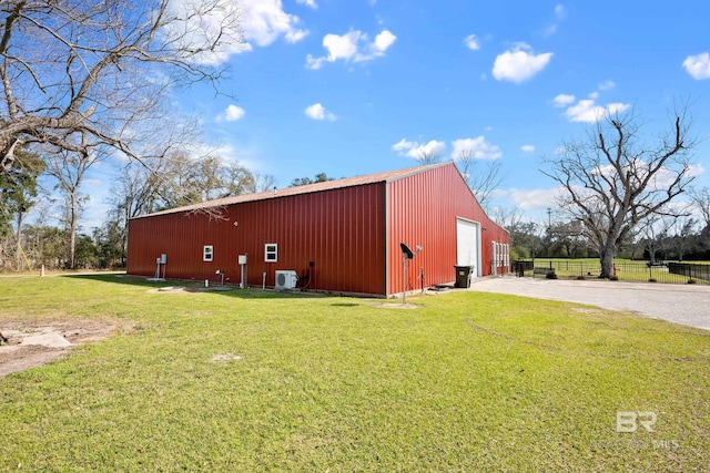 view of side of home with fence, an outdoor structure, a lawn, and an outbuilding