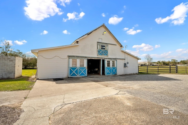 exterior space featuring a barn, driveway, fence, and an outbuilding