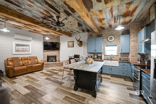 kitchen featuring an AC wall unit, range with two ovens, a sink, and blue cabinets