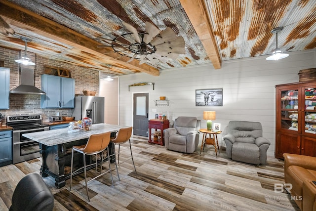 kitchen with light wood-style floors, wall chimney exhaust hood, stainless steel appliances, and open floor plan