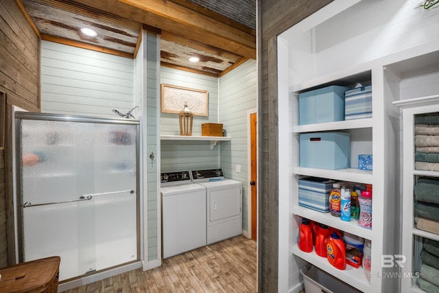 washroom with laundry area, wooden walls, washer and clothes dryer, and light wood-style floors