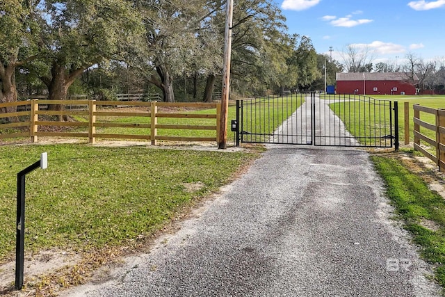 view of gate with a rural view, a yard, and fence