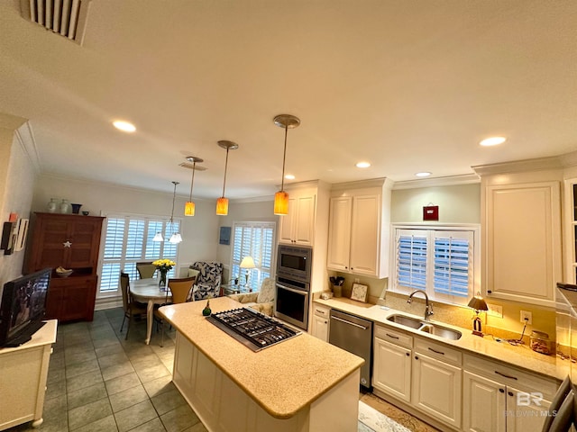 kitchen with a center island, sink, white cabinets, stainless steel appliances, and decorative light fixtures