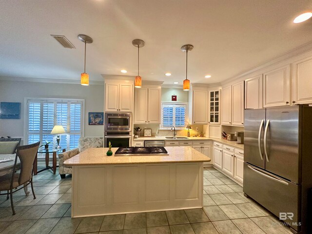 kitchen featuring appliances with stainless steel finishes, white cabinetry, sink, and decorative light fixtures