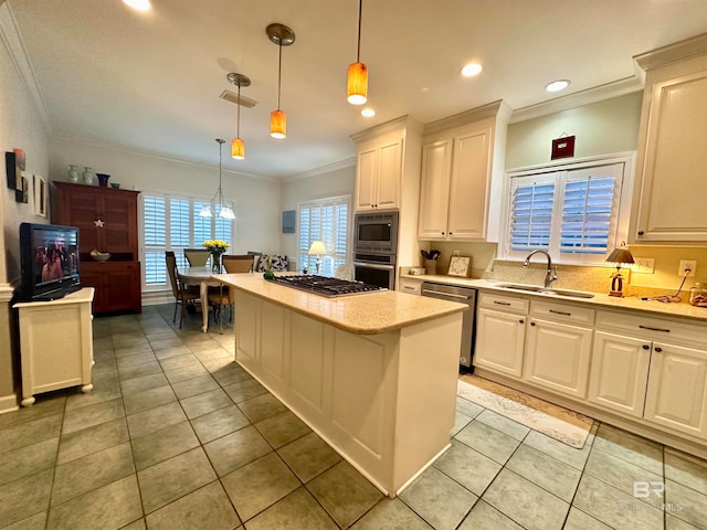 kitchen featuring appliances with stainless steel finishes, hanging light fixtures, white cabinets, a kitchen island, and sink