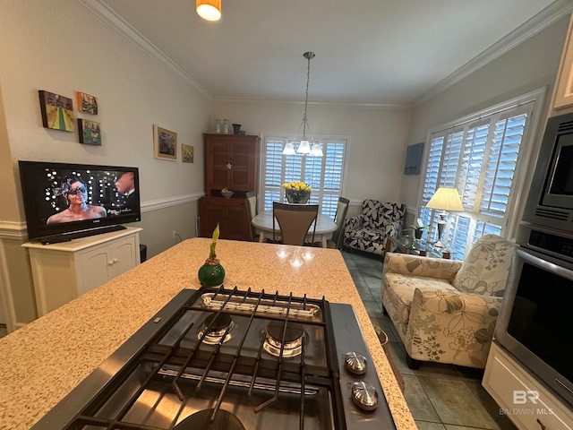 kitchen with appliances with stainless steel finishes, hanging light fixtures, dark tile patterned floors, ornamental molding, and a notable chandelier