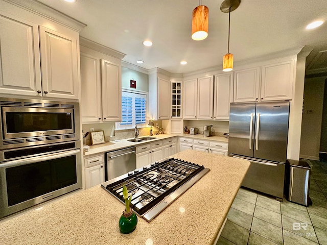 kitchen featuring appliances with stainless steel finishes, hanging light fixtures, light stone counters, white cabinets, and sink