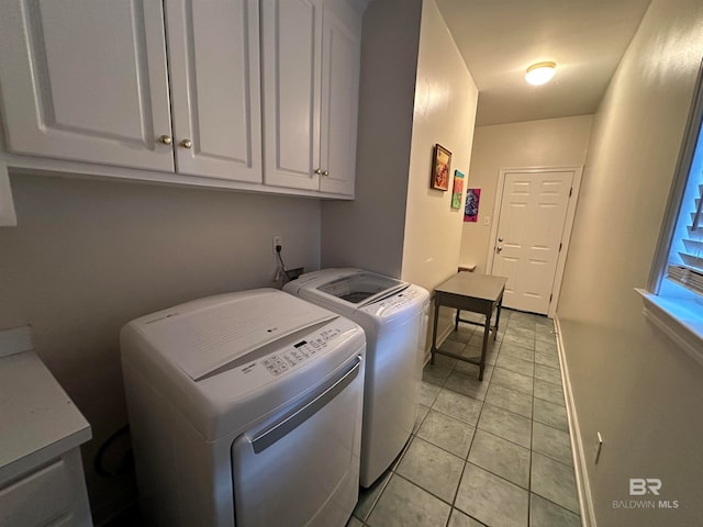 clothes washing area with light tile patterned floors, washer and dryer, and cabinets