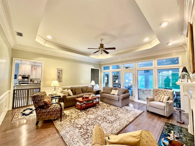 living room with ceiling fan, ornamental molding, a raised ceiling, and hardwood / wood-style floors