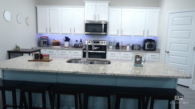 kitchen featuring sink, white cabinetry, an island with sink, and appliances with stainless steel finishes