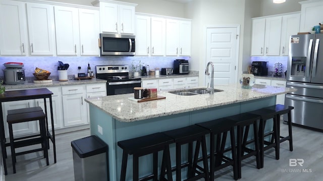 kitchen featuring white cabinetry, sink, light hardwood / wood-style flooring, a kitchen island with sink, and appliances with stainless steel finishes