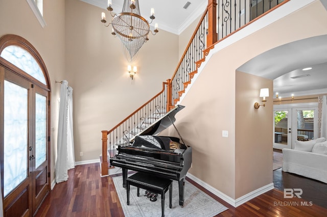 entrance foyer with ornamental molding, a high ceiling, dark wood-type flooring, and french doors