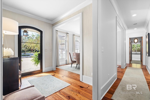 entryway with wood-type flooring and crown molding