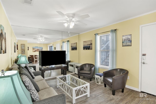 living room with hardwood / wood-style flooring, ornamental molding, and ceiling fan