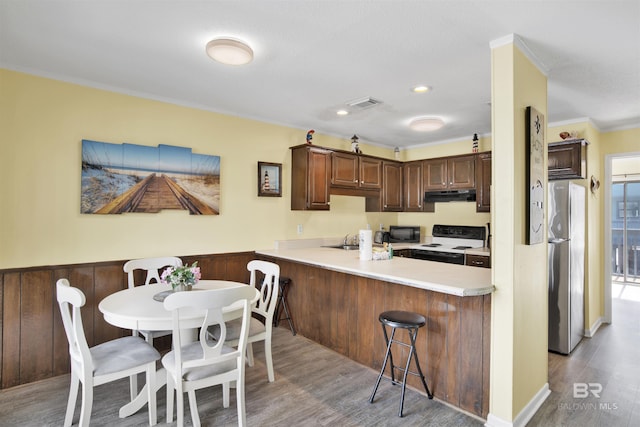 kitchen with electric range, stainless steel refrigerator, ornamental molding, kitchen peninsula, and light hardwood / wood-style floors