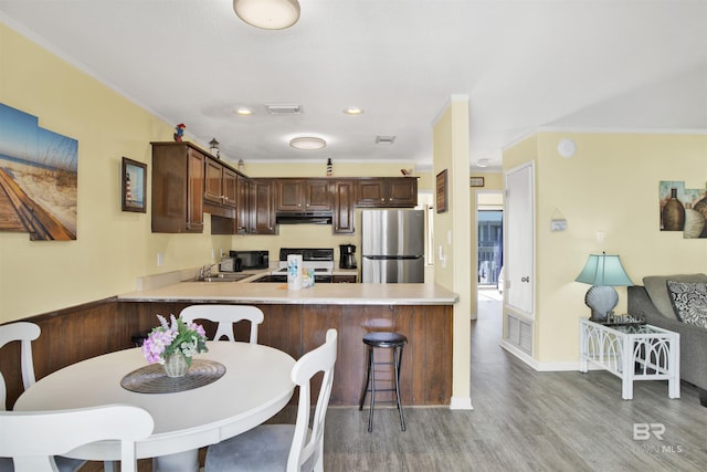 kitchen featuring sink, range, light wood-type flooring, stainless steel fridge, and kitchen peninsula