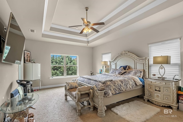 carpeted bedroom with ceiling fan, a raised ceiling, and ornamental molding