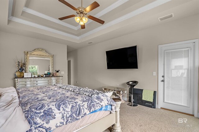 carpeted bedroom with a tray ceiling, ceiling fan, and crown molding