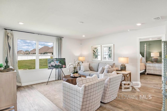 living room featuring baseboards, visible vents, wood finished floors, and recessed lighting