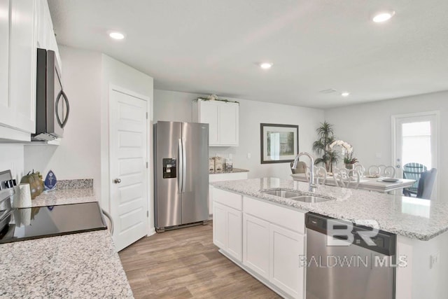 kitchen featuring stainless steel appliances, a kitchen island with sink, sink, light hardwood / wood-style flooring, and white cabinetry