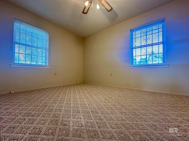 carpeted spare room with ceiling fan, a wealth of natural light, and vaulted ceiling