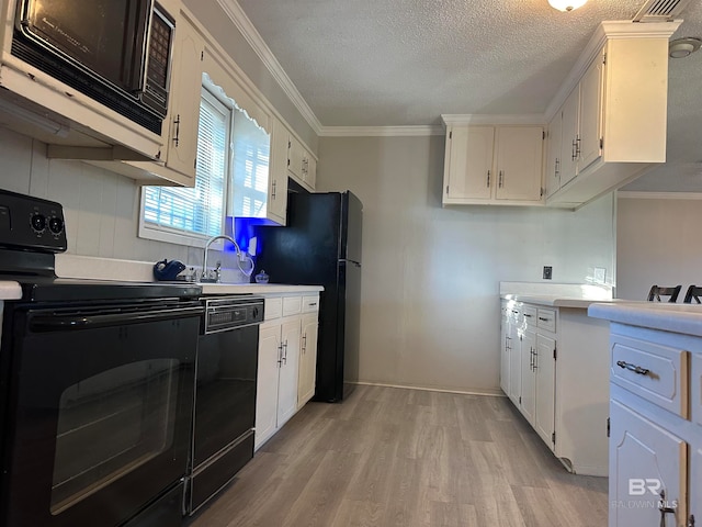 kitchen featuring white cabinets, light wood-type flooring, ornamental molding, and black appliances