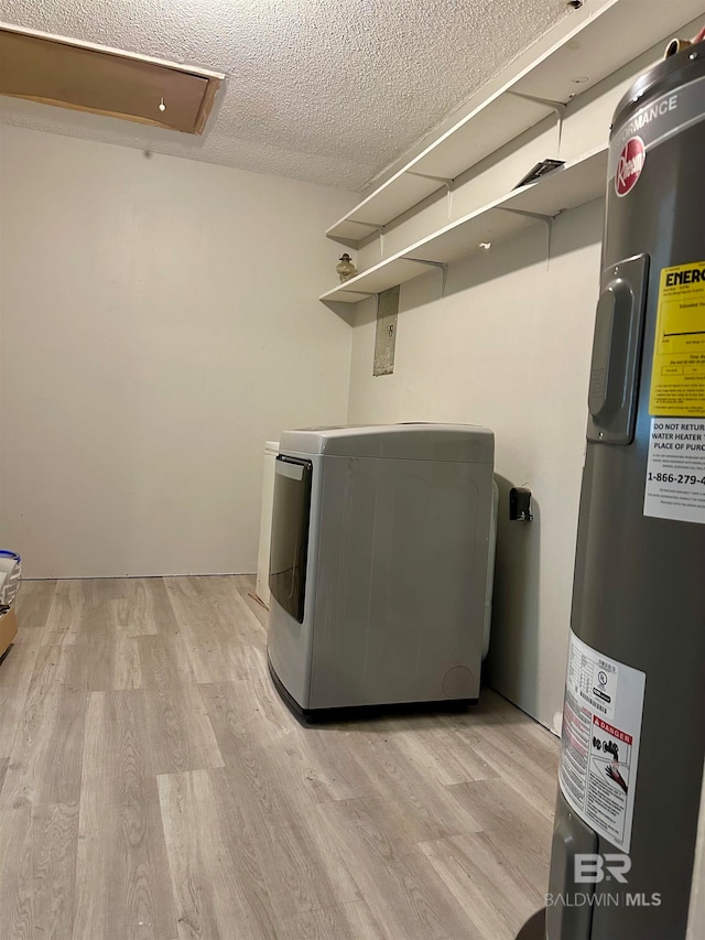 laundry area featuring a textured ceiling, light hardwood / wood-style flooring, washer / clothes dryer, and water heater