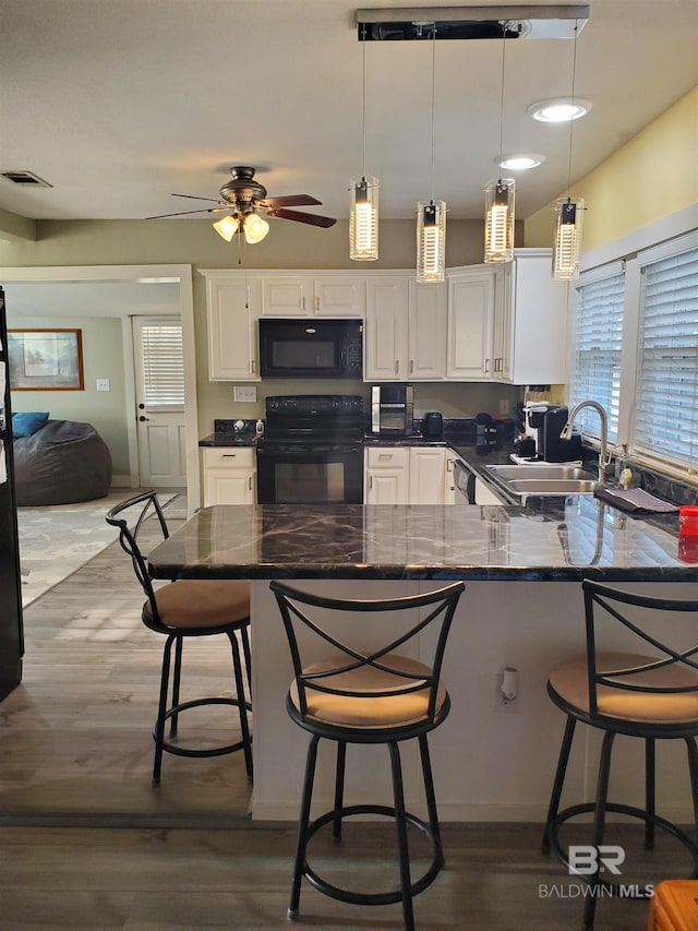 kitchen featuring white cabinets, visible vents, a sink, and black appliances