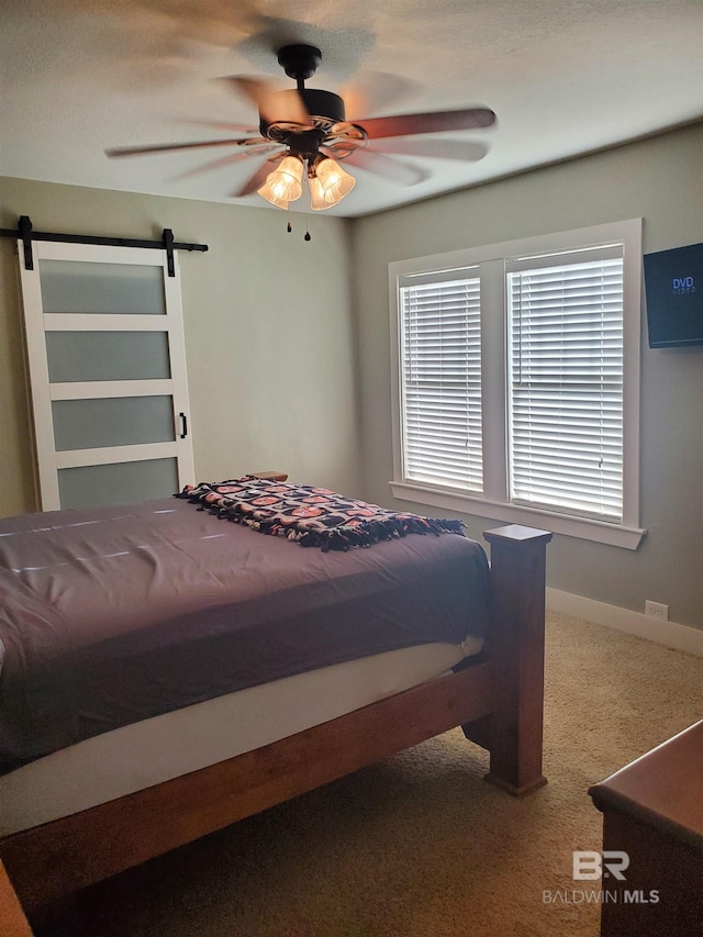 bedroom featuring carpet floors, a barn door, and a ceiling fan