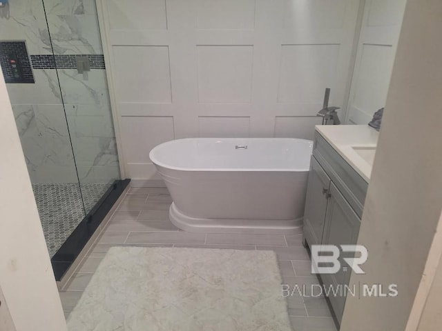 bathroom with a freestanding tub, a marble finish shower, and vanity