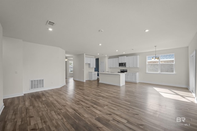 unfurnished living room with visible vents, recessed lighting, an inviting chandelier, and wood finished floors