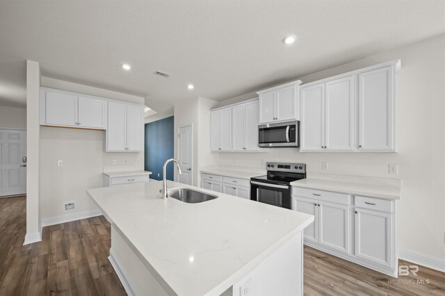 kitchen featuring visible vents, an island with sink, a sink, white cabinets, and appliances with stainless steel finishes