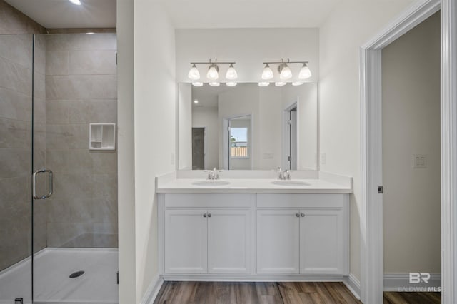 full bath featuring double vanity, a shower stall, wood finished floors, and a sink