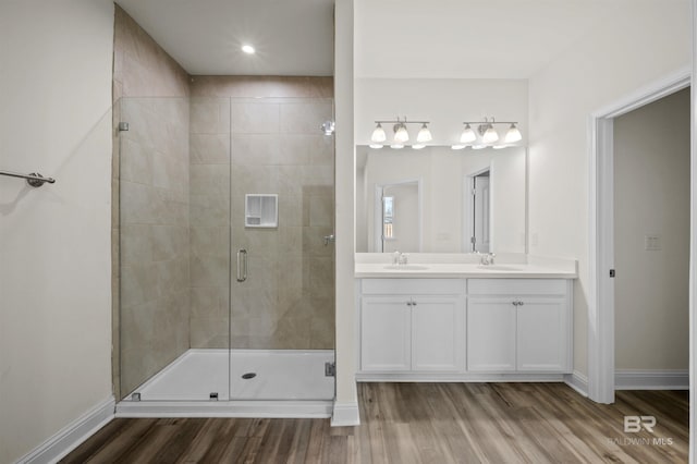 bathroom featuring a shower stall, wood finished floors, baseboards, and a sink
