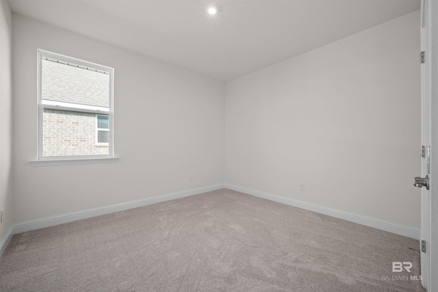 carpeted spare room featuring baseboards