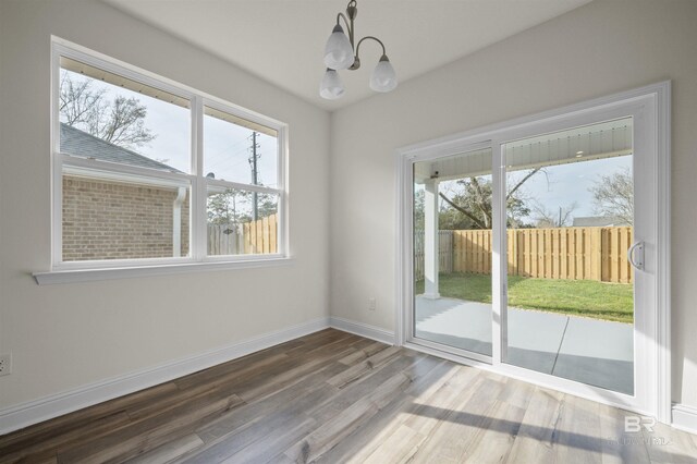 unfurnished dining area featuring a chandelier, baseboards, and wood finished floors