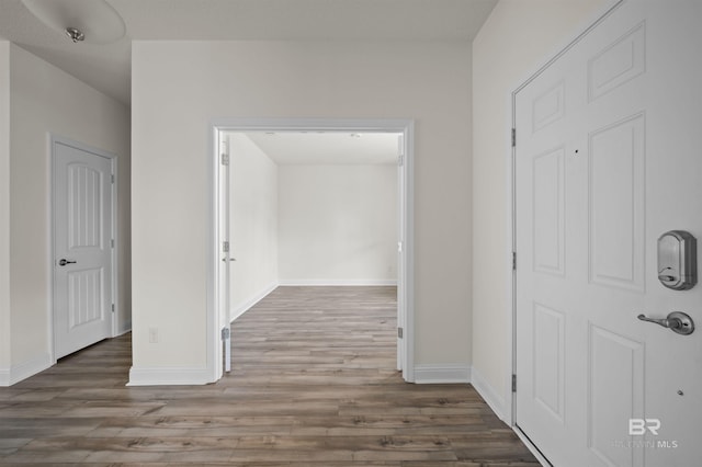 corridor featuring wood finished floors and baseboards