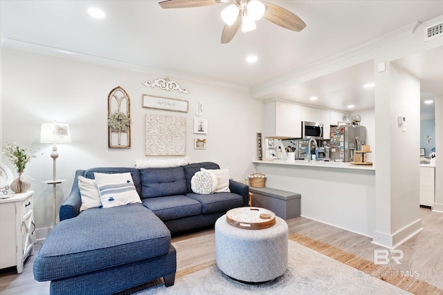 living room with ornamental molding, ceiling fan, and light hardwood / wood-style flooring